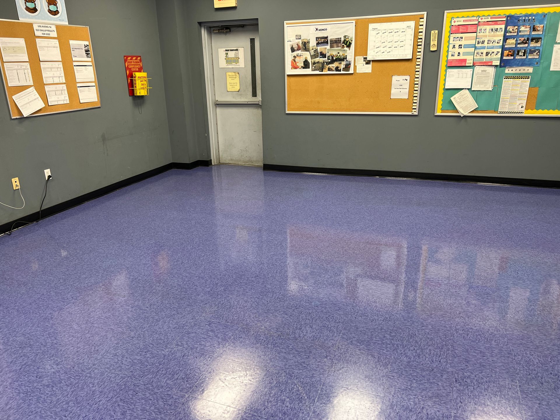 A room with a purple floor and bulletin boards on the wall