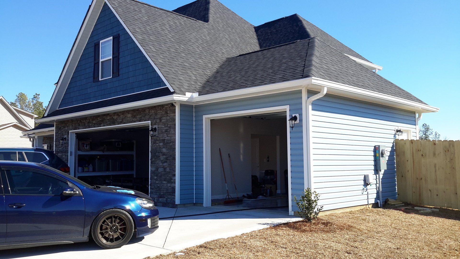 A gray house with a white-columned porch, chimney, and gray shingled roof. 