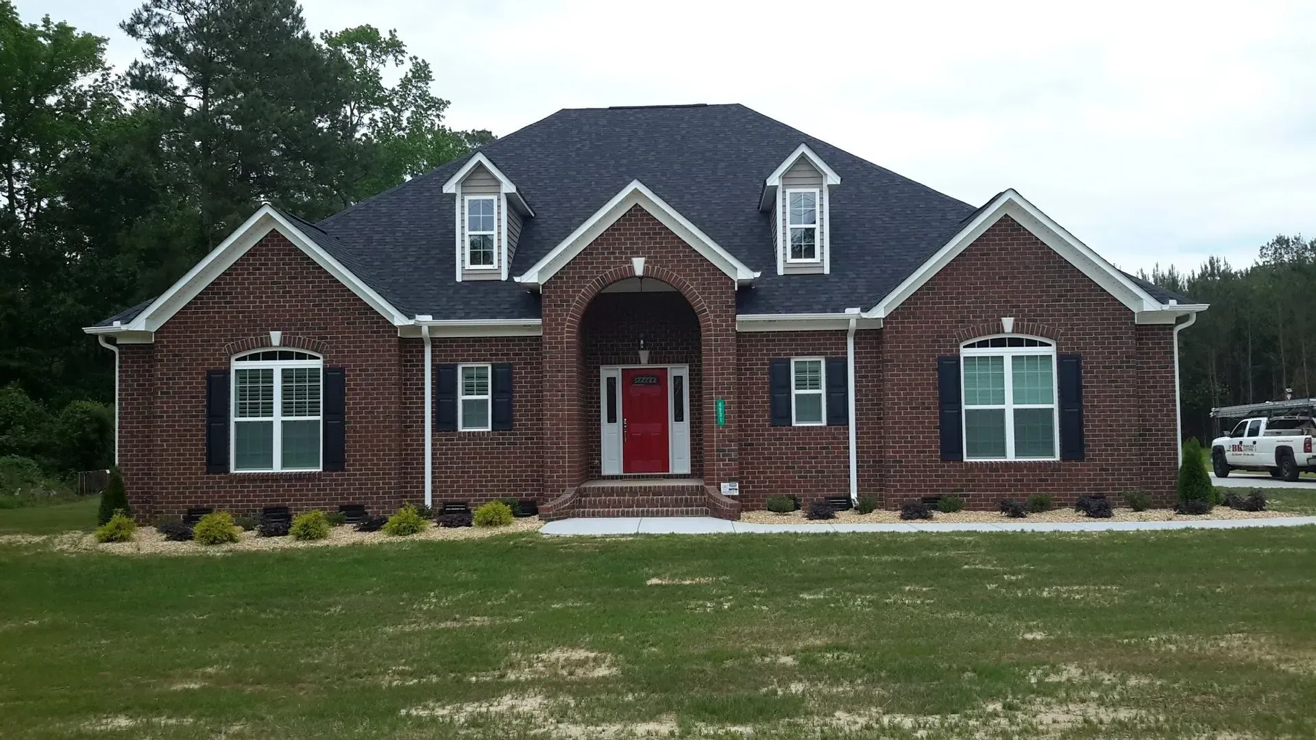 Two-story house with tan stucco walls, brown roof, and wooden accents against a blue sky.