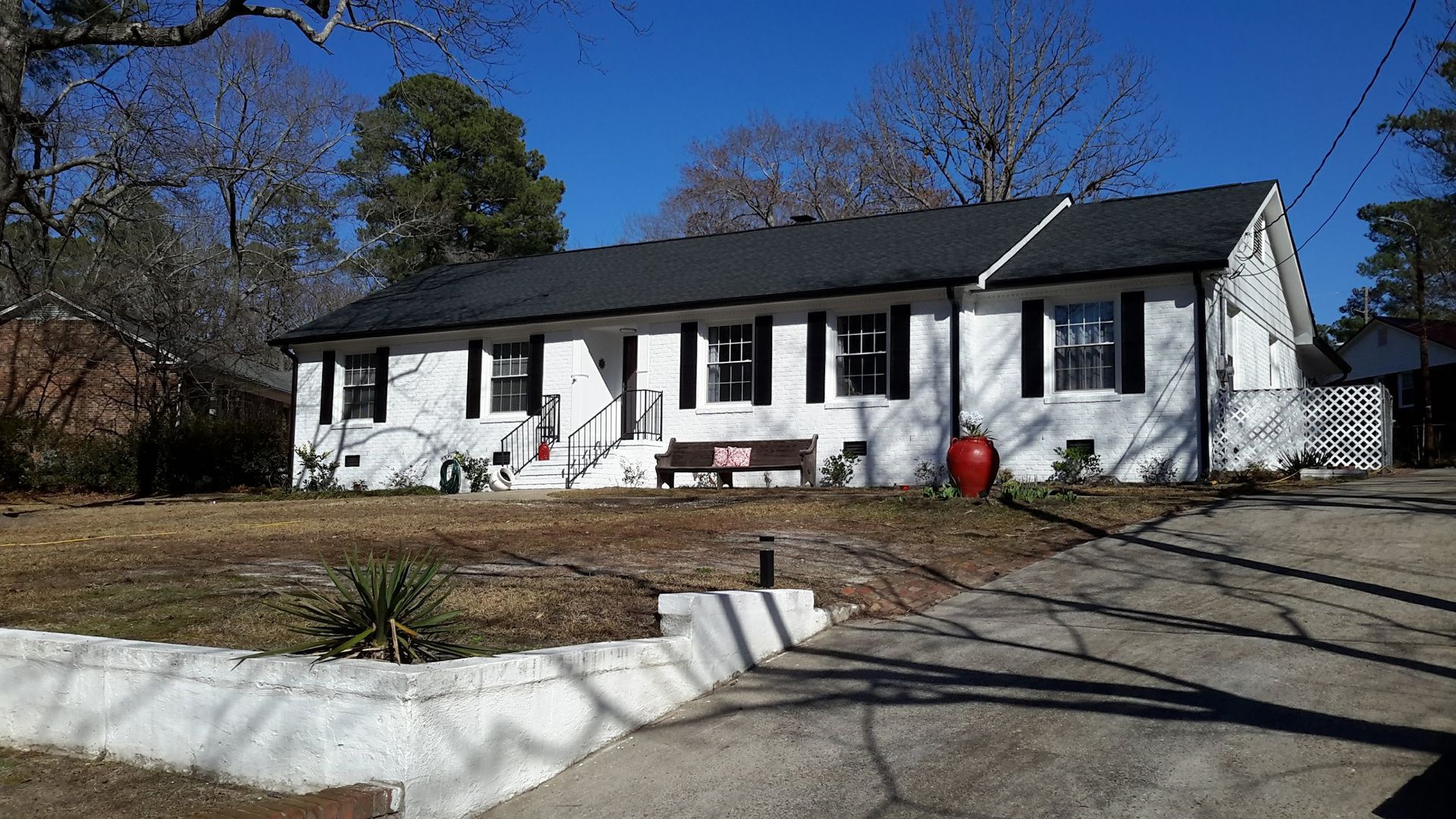A two-story gray house with a garage and blue trim, set on a concrete driveway with a lawn.