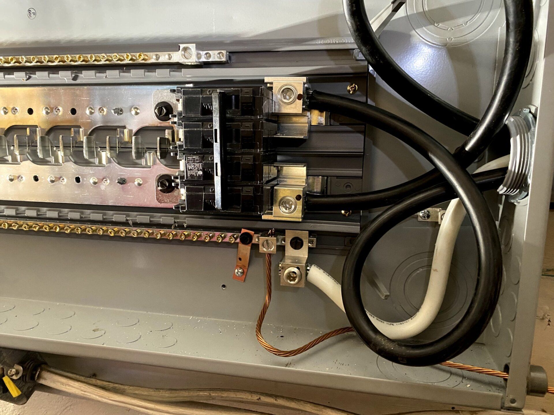 Electrical panel interior, showing circuit breakers, wiring, and grounding connections within a metal box.