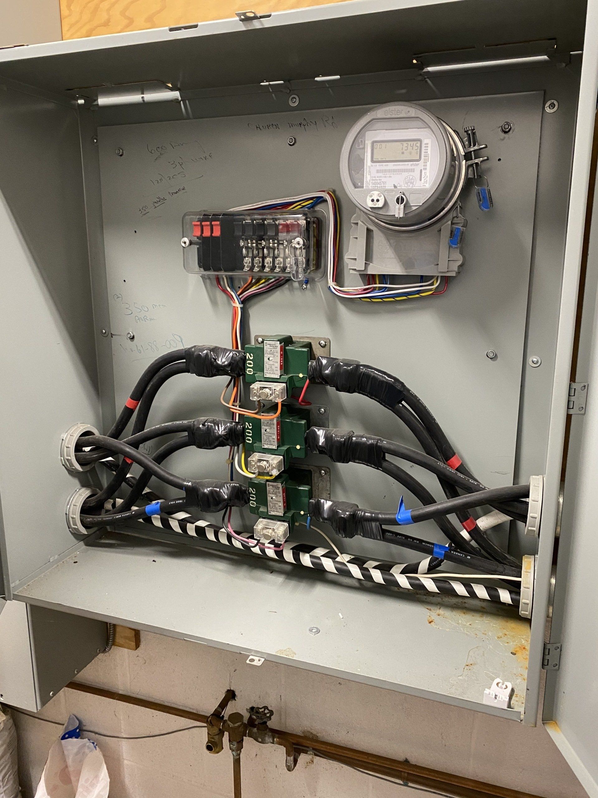 Open electrical panel with meter, wiring, and circuit boards.