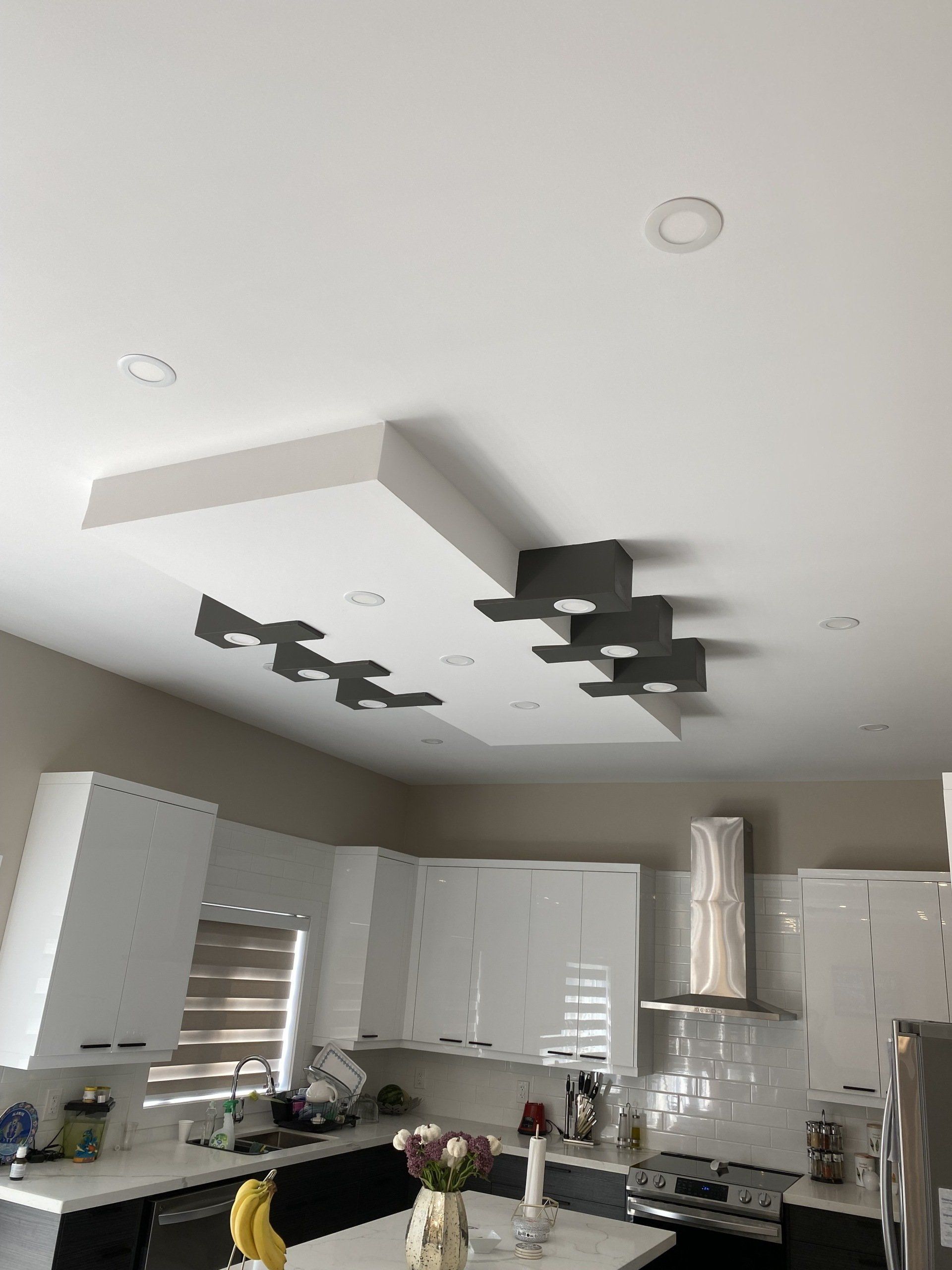 Modern kitchen with white cabinets, stainless steel appliances, and decorative ceiling lights.