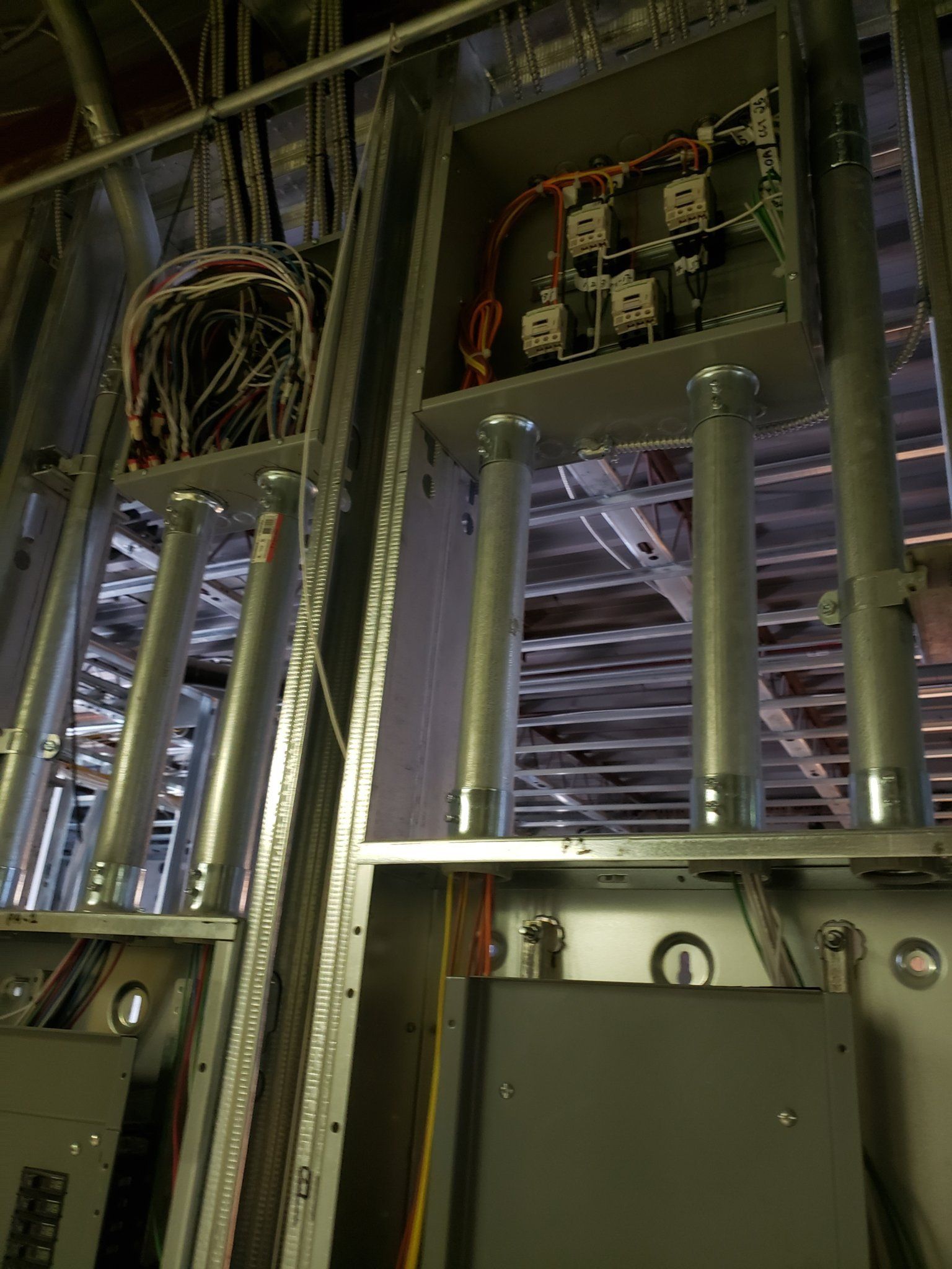 Electrical wiring installation with conduits, boxes, and panels in a steel-framed wall.