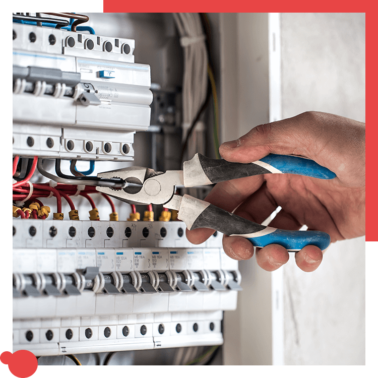 Hand using pliers on electrical panel wires.
