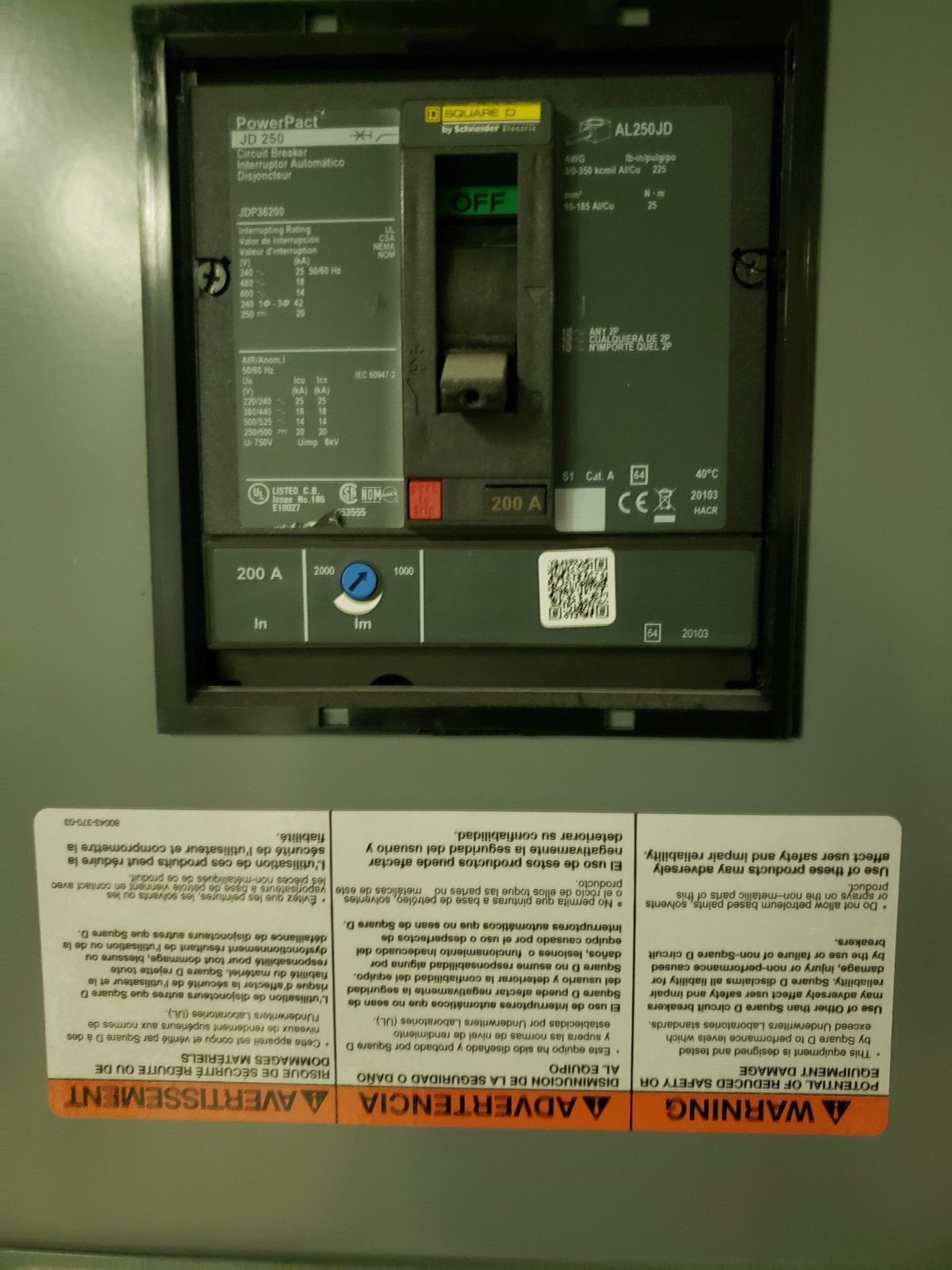 Electrical panel with a circuit breaker, inside a gray box, with a warning label below.