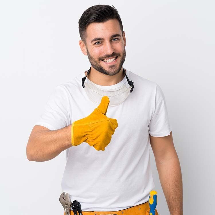 Man with yellow glove gives a thumbs up, wearing a white shirt and tool belt, smiles.
