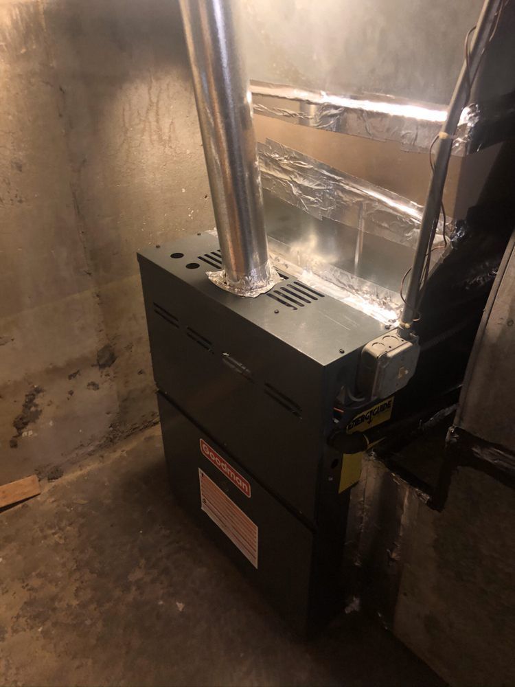 a gas furnace is sitting in a basement next to a wall .