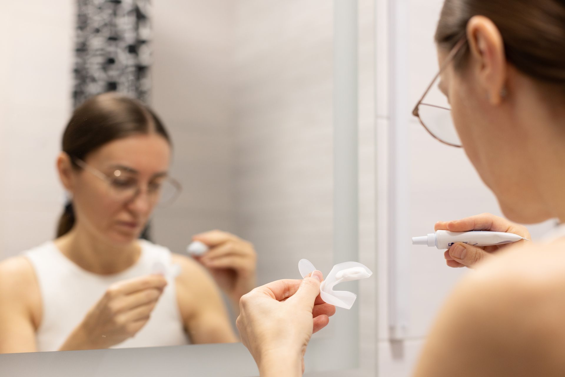 Close-up of a person holding a silicone tray for a DIY teeth whitening treatment. Close-up of a person holding a silicone tray for a DIY teeth whitening treatment.