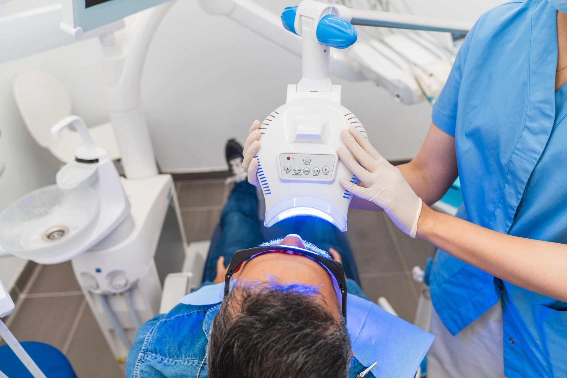 A man is getting his teeth whitened in a dentist's office.