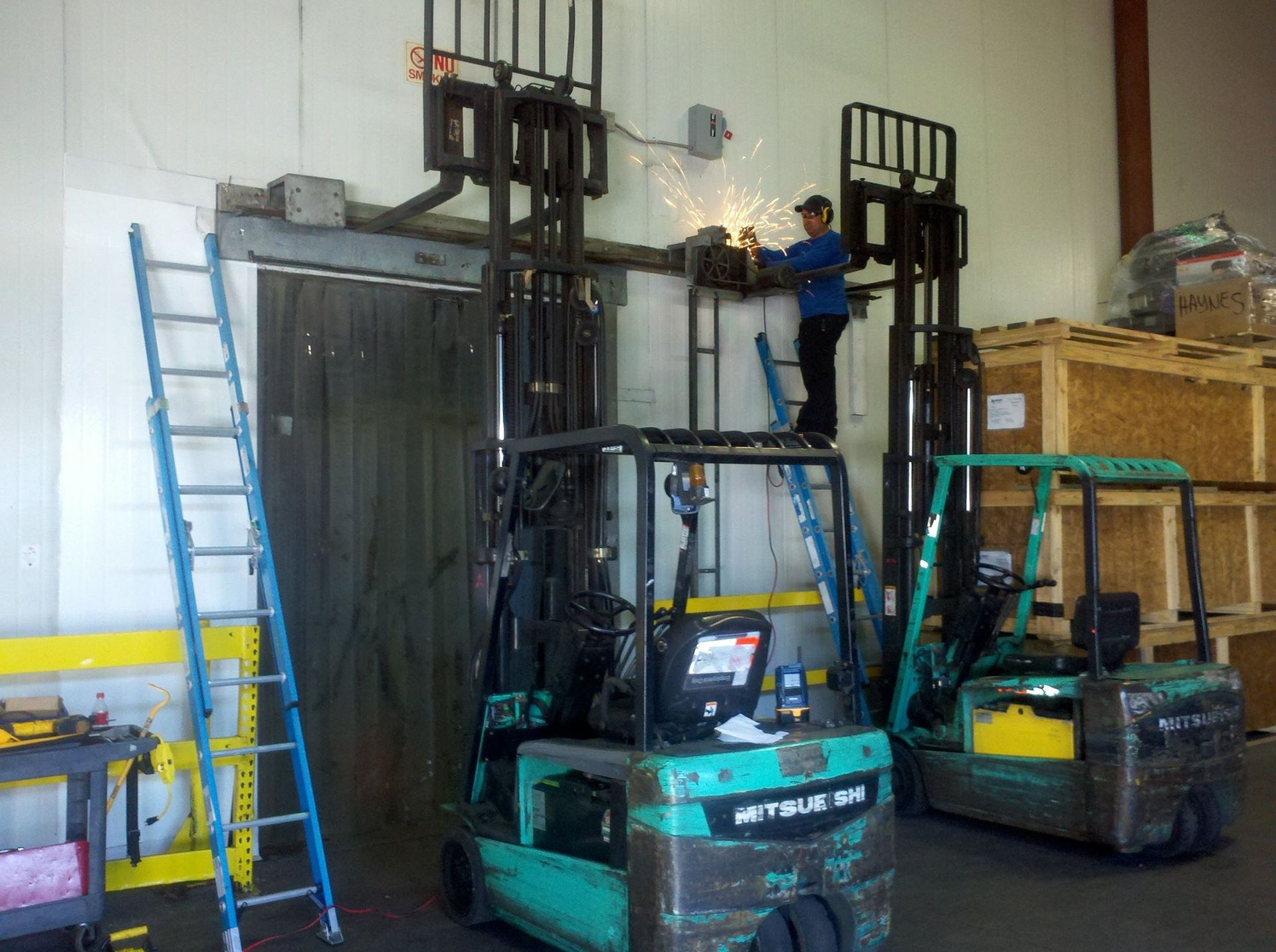 A man is working on a forklift in a warehouse