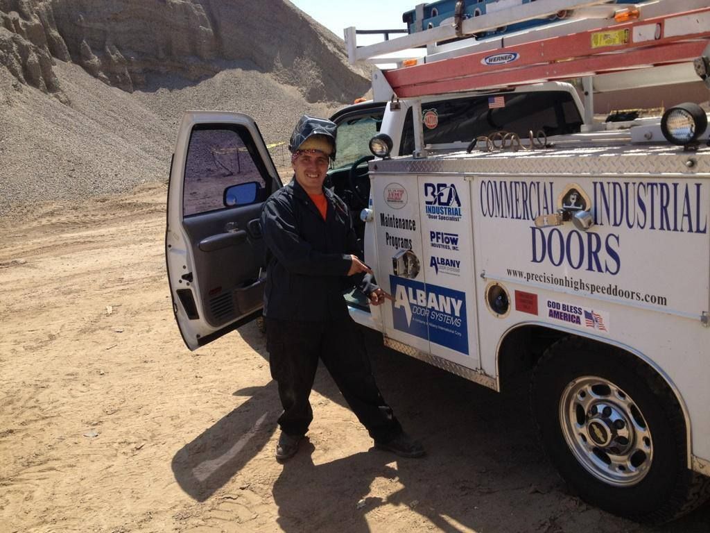 A man is standing in front of a truck that says industrial doors