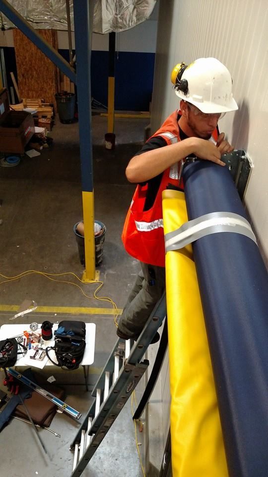 A man wearing a hard hat and safety vest is standing on a ladder.