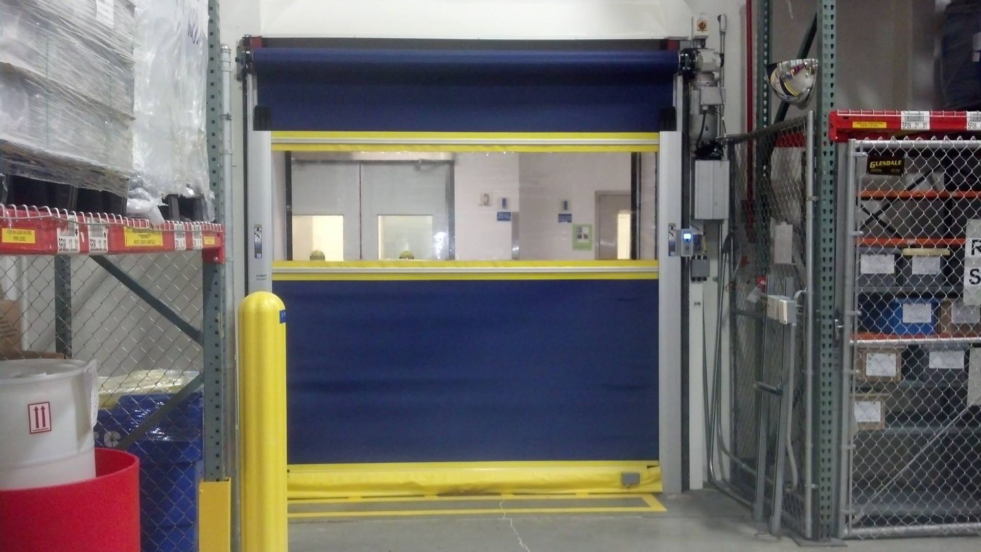 A blue and yellow door is open in a warehouse.