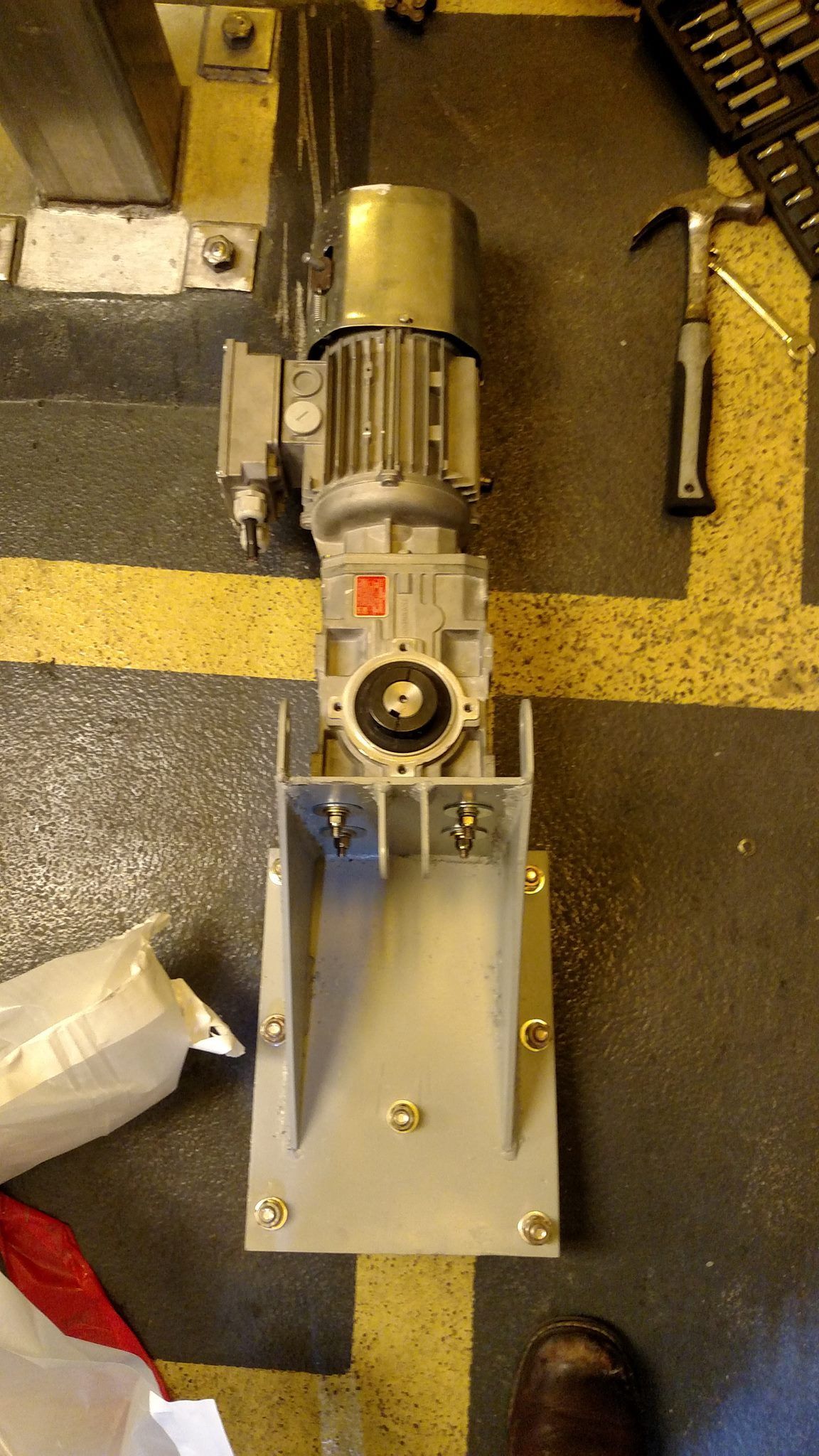 A machine is sitting on the floor next to a hammer.