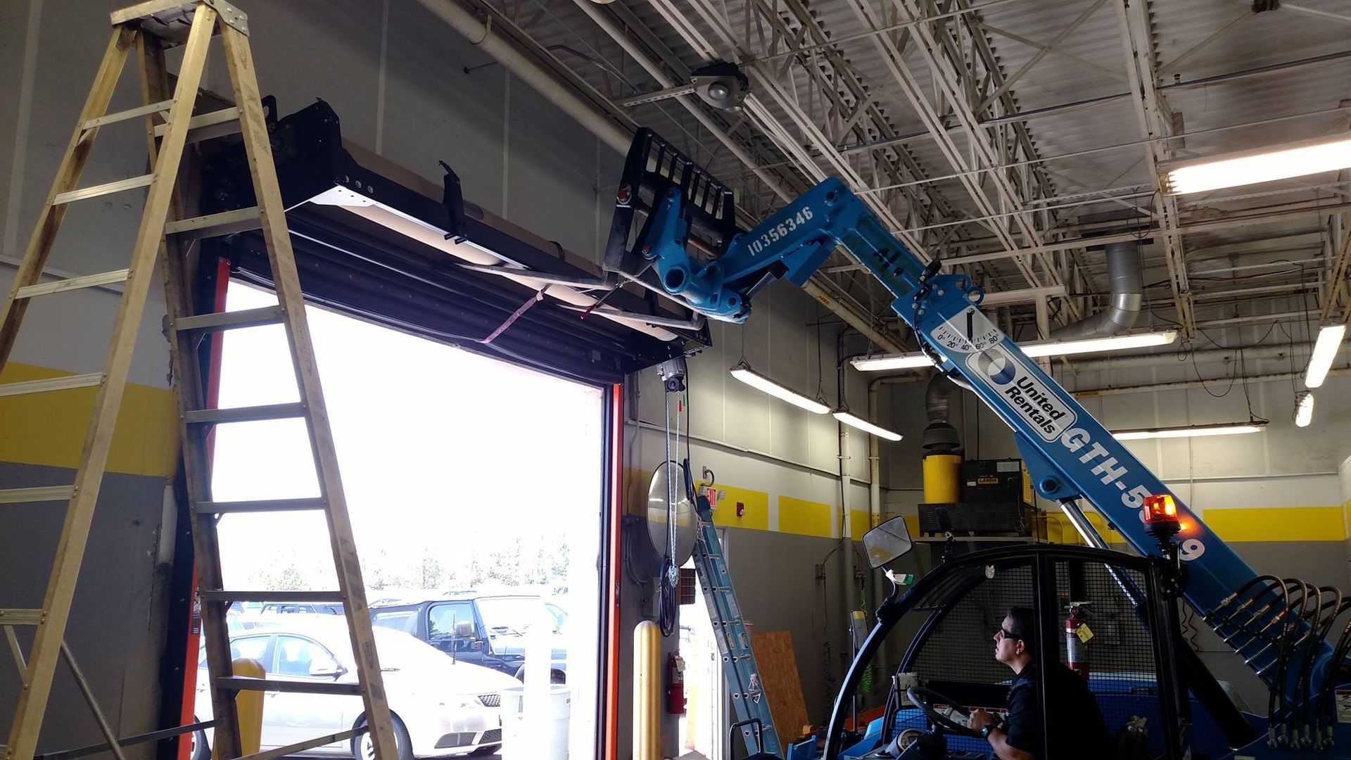 A ladder is sitting next to a crane in a garage.
