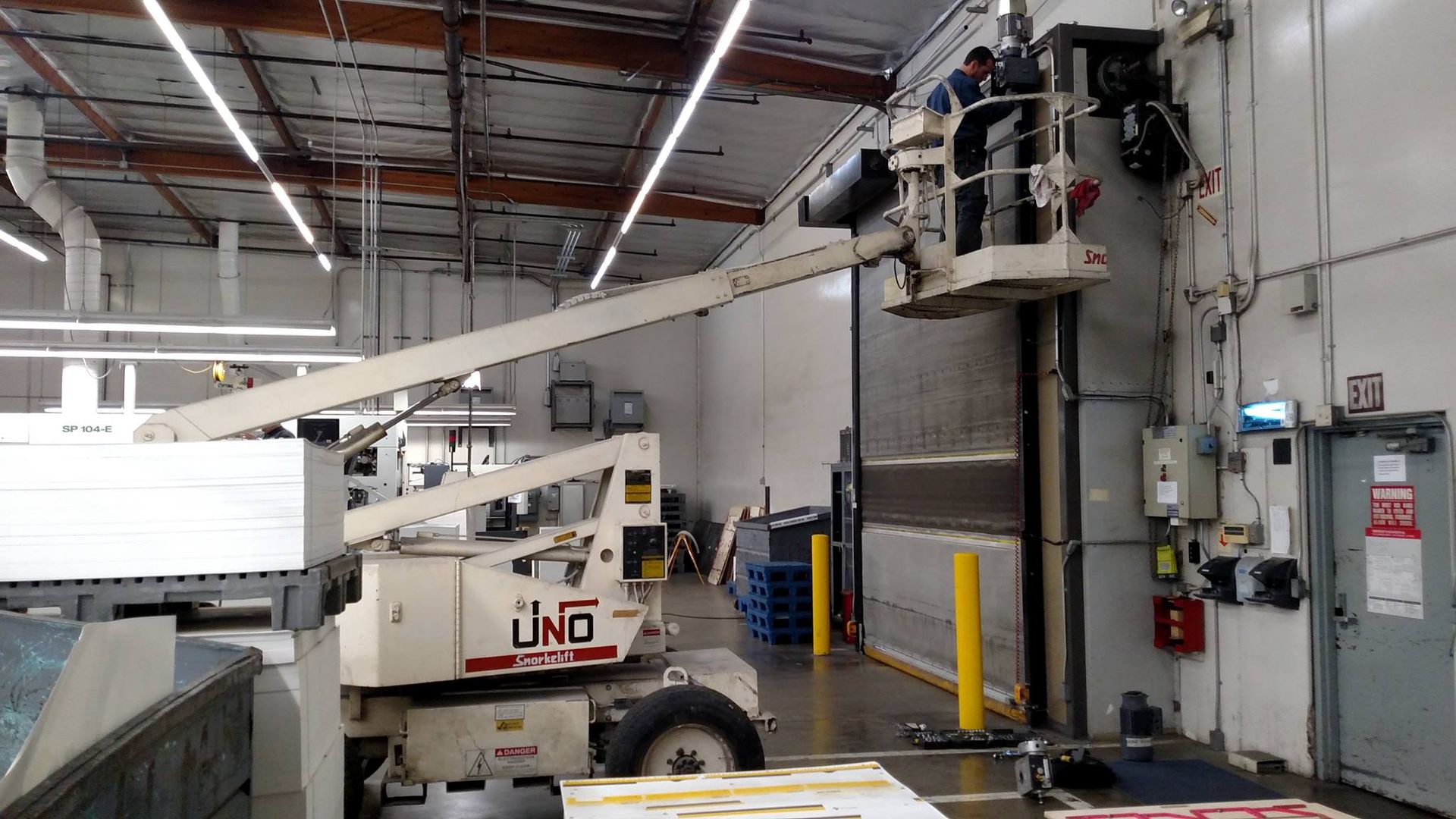 A man is working on a lift in a warehouse.
