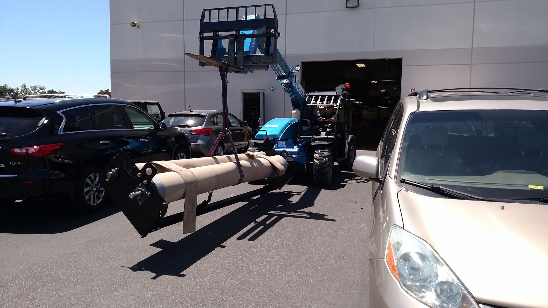 A large pipe is being lifted by a crane in a parking lot