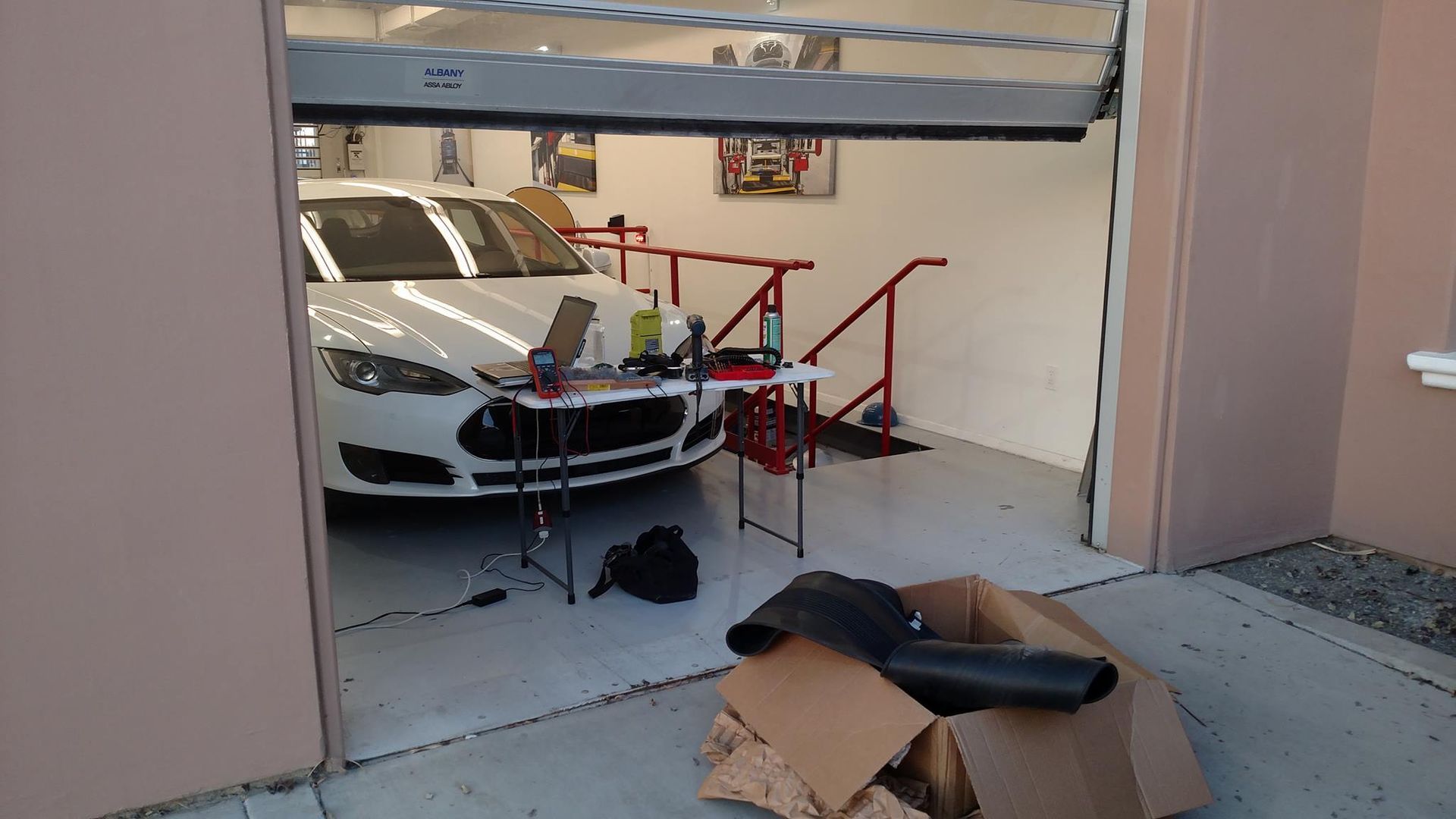 A white car is parked in a garage next to a cardboard box.