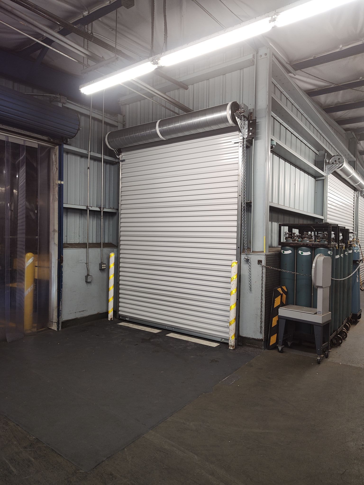A warehouse with a large garage door and a lot of containers.