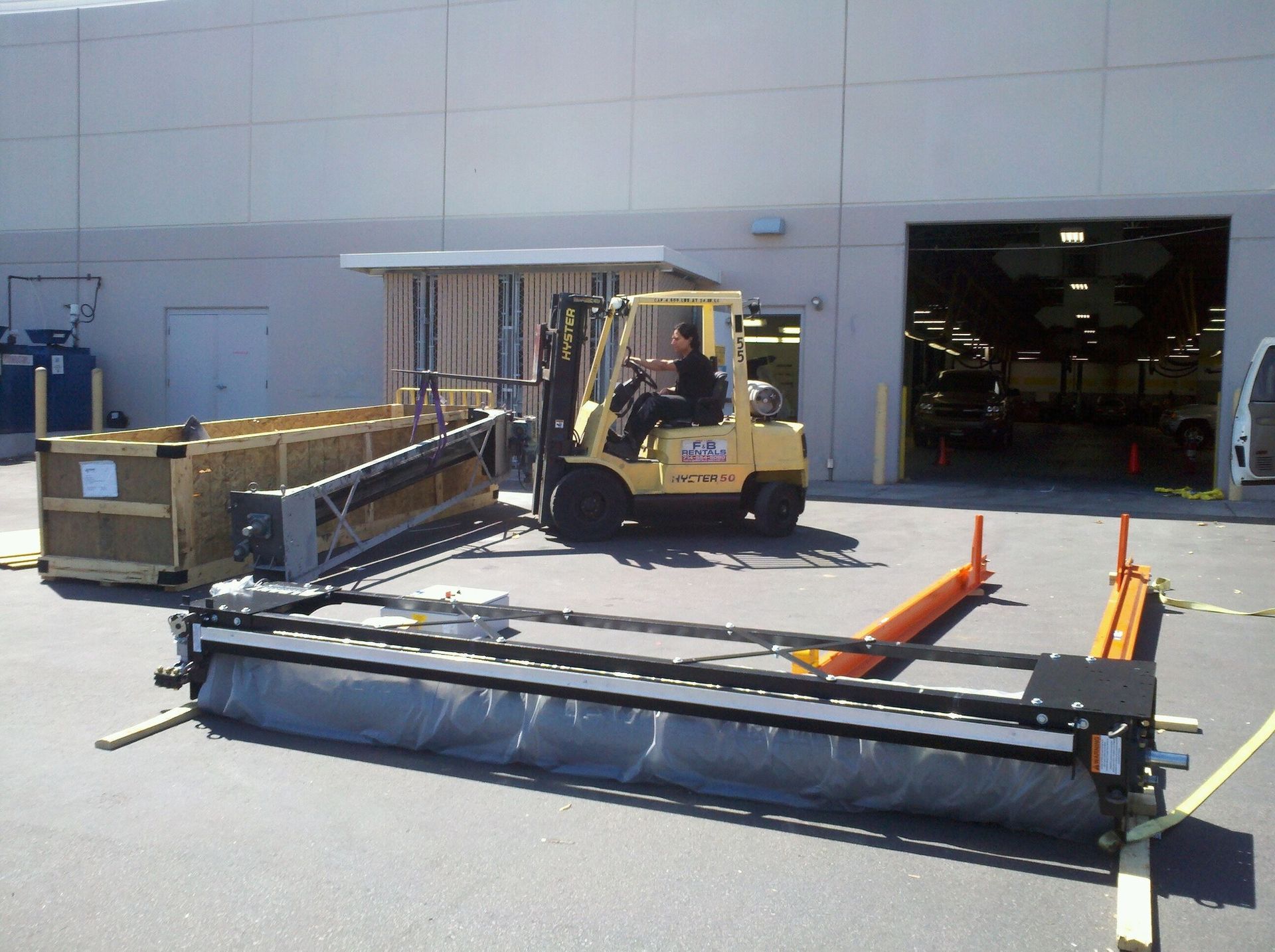 A man is driving a yellow forklift in a parking lot