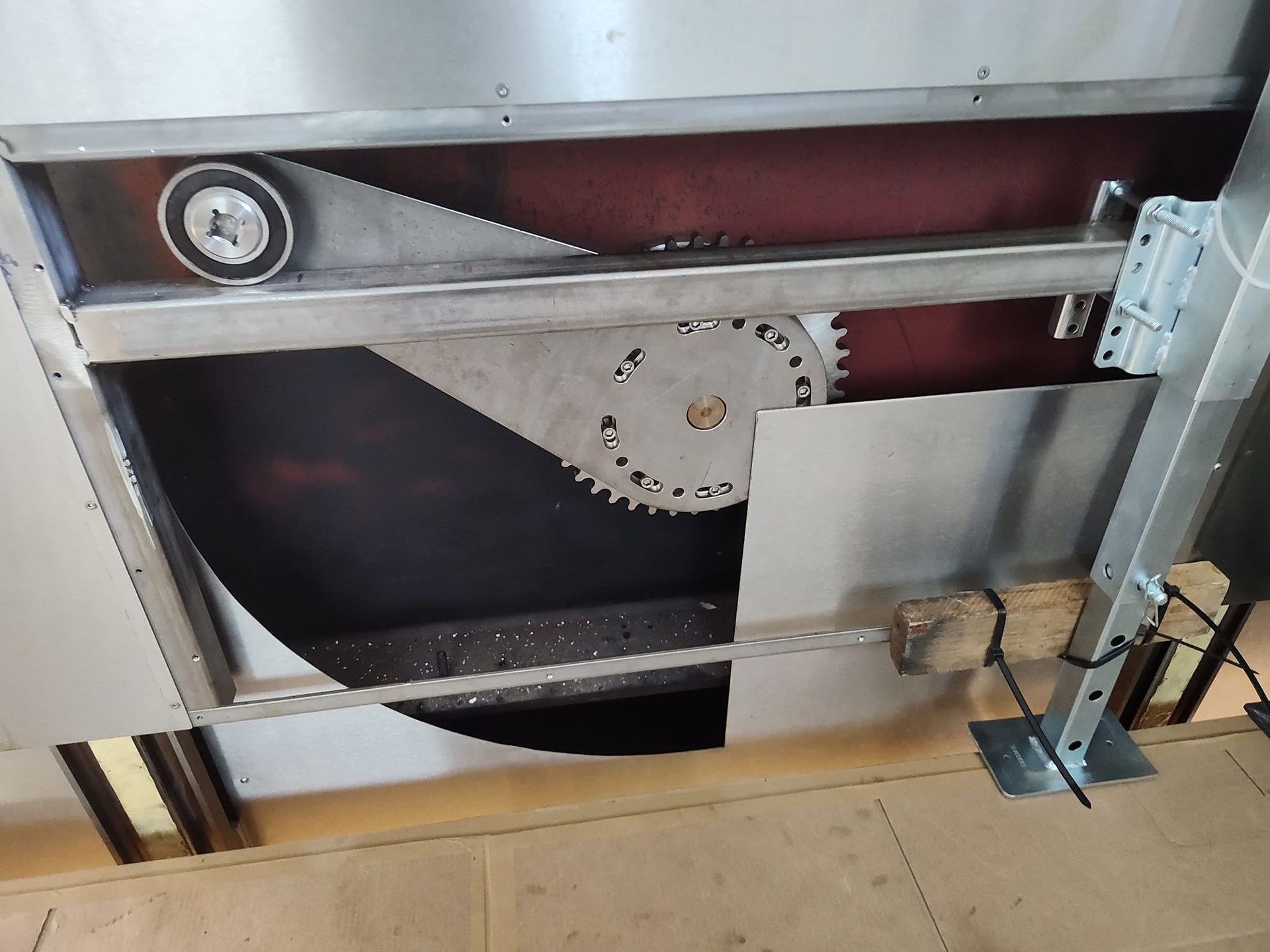 Mechanical saw with exposed circular blade and drive belt system within a metal frame.