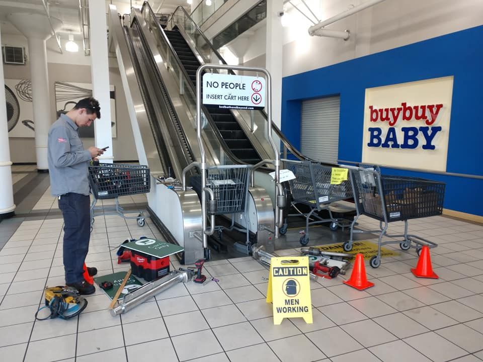 A man is working on an escalator in front of a sign that says buybuy baby