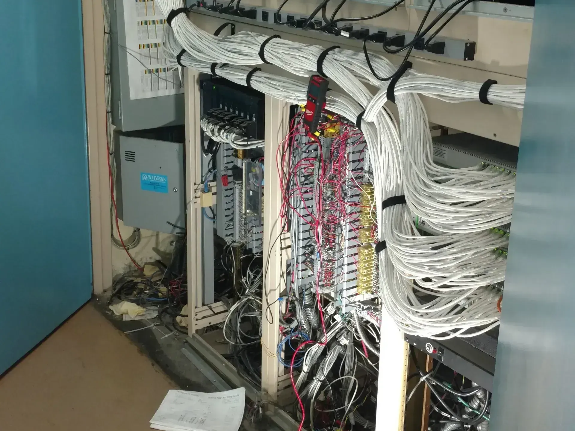 A bunch of wires are hanging from a wall in a room