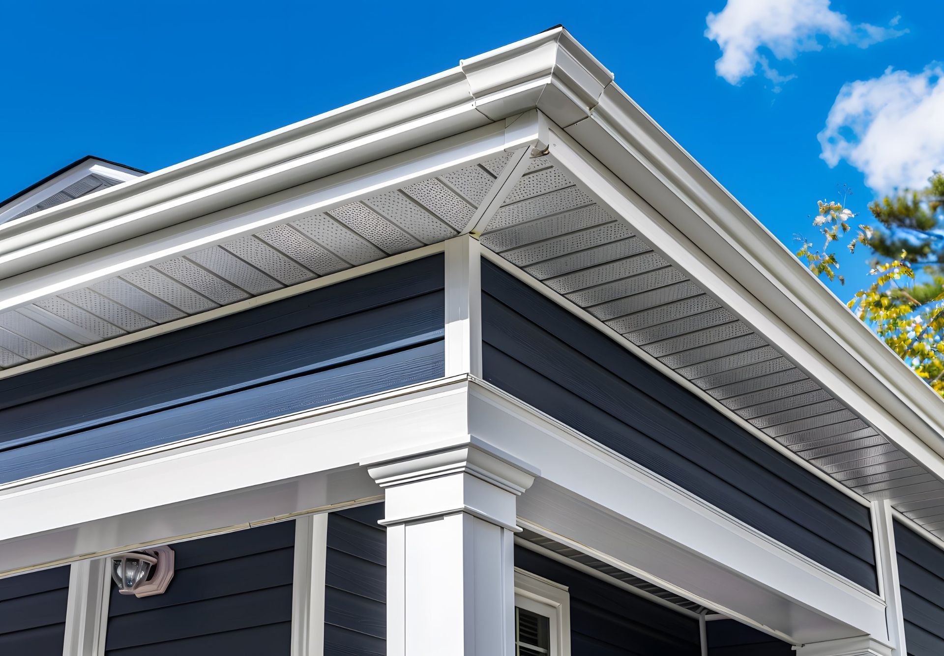 Blue house exterior with white trim, soffit, and gutters against a blue sky.