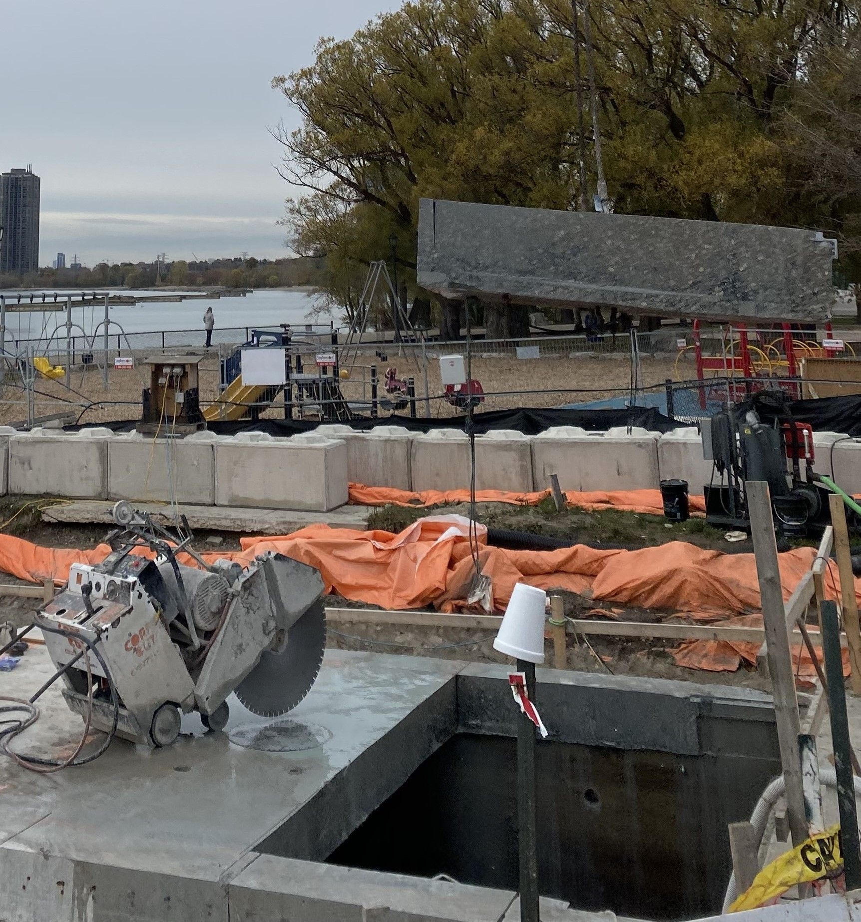 Construction site with a concrete saw cutting a square opening.