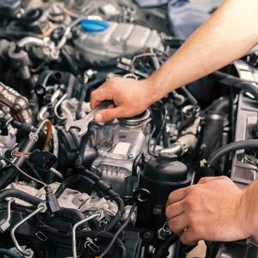 A man is working on a car engine with a wrench.