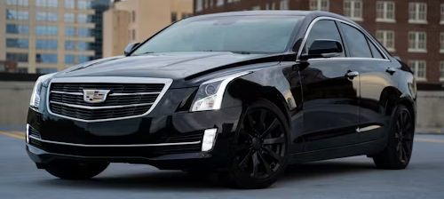 Black Cadillac sedan parked on a rooftop, with city buildings in the background.