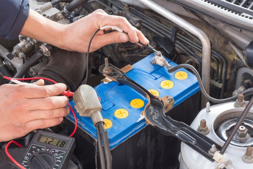 A Mechanic Uses a Multimeter to Test a Blue Car Battery — Roberts Automotive & Industrial in Brighton, TAS