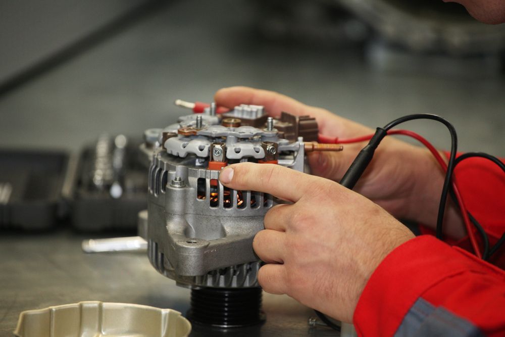 A Technician in a Red Jacket Uses a Multimeter to Test a Car Alternator — Roberts Automotive & Industrial in Brighton, TAS