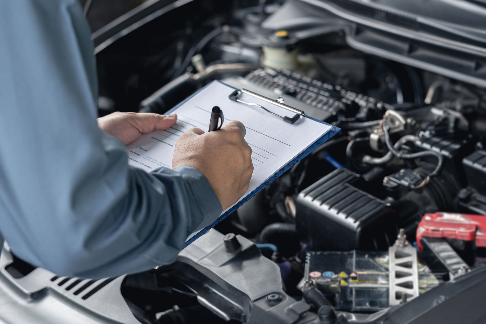 A Mechanic Writes on a Clipboard While Inspecting an Open Car Engine. — Roberts Automotive & Industrial in Brighton, TAS