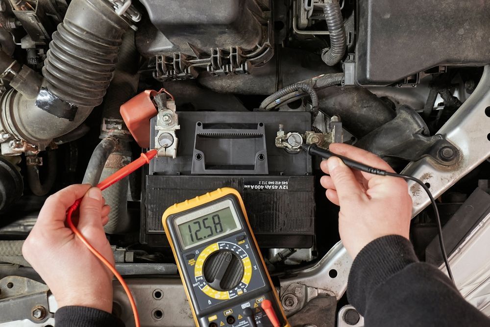 Hands Holding Multimeter Probes to a Car Battery to Measure Voltage — Roberts Automotive & Industrial in Brighton, TAS