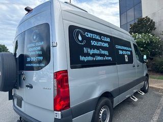 A silver van is parked in a parking lot in front of a building.