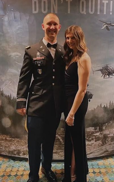A man in a military uniform and a woman in a black dress are posing for a picture.