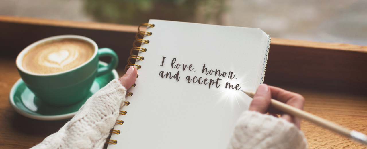 a woman's hands as she writes a self-affirming mantra of self-love in her journal, with a cup of coffee