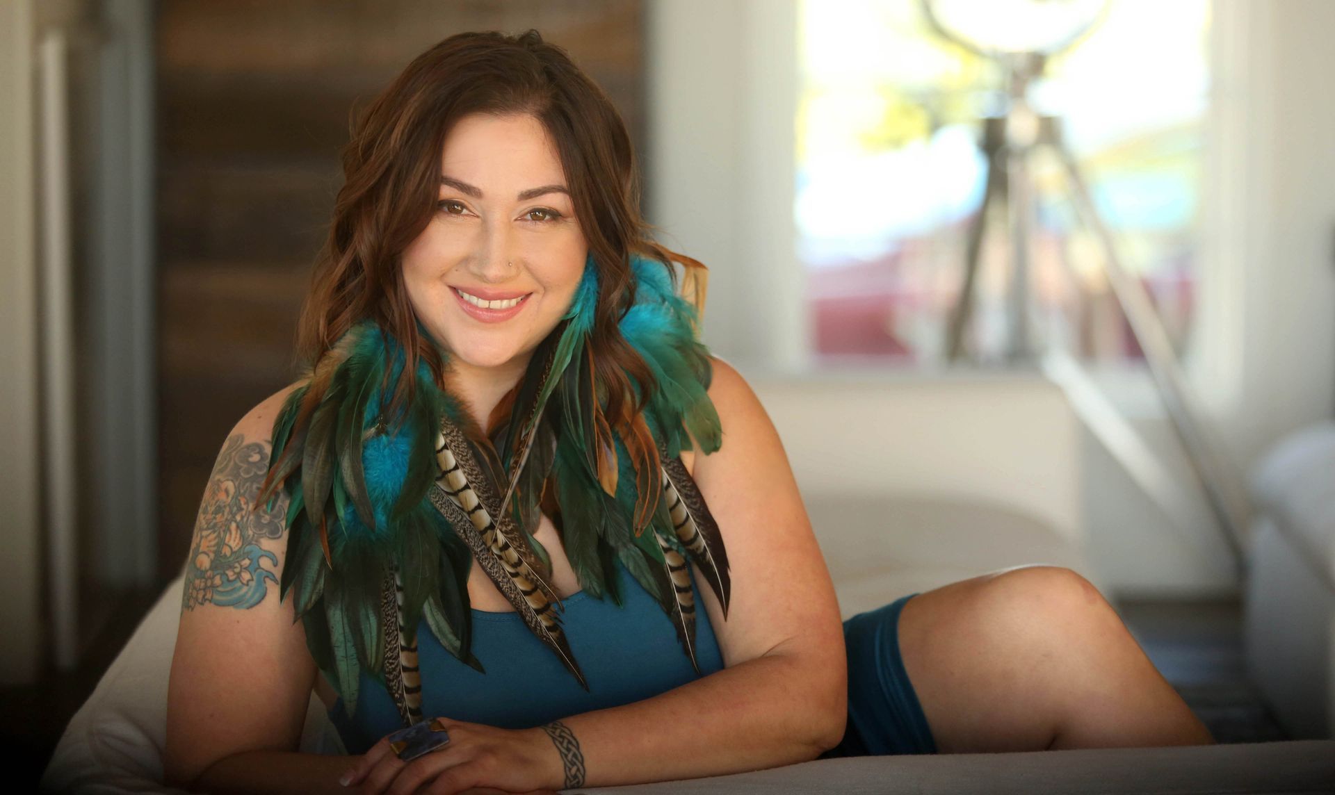 A practitioner holds a singing bowl above a person resting on a mat during a sound healing session.