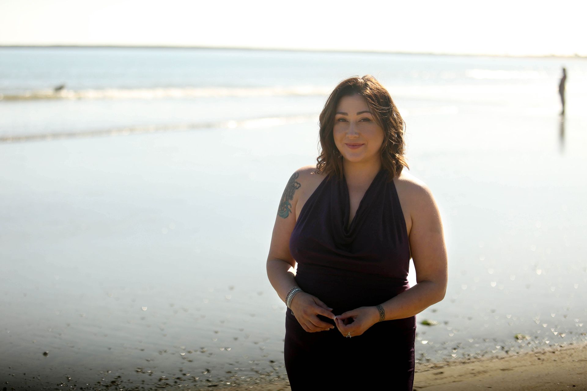 A person receiving a sound bath, with a practitioner holding a singing bowl over them, surrounded by various metal bowls.