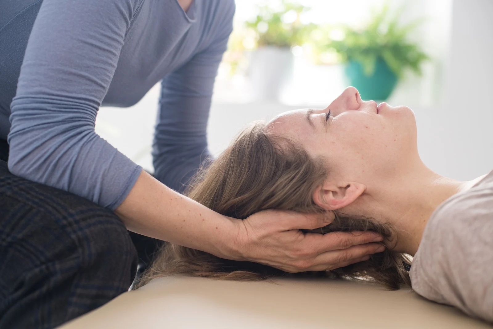 A person receives head and neck therapeutic massage while lying down on a treatment table.