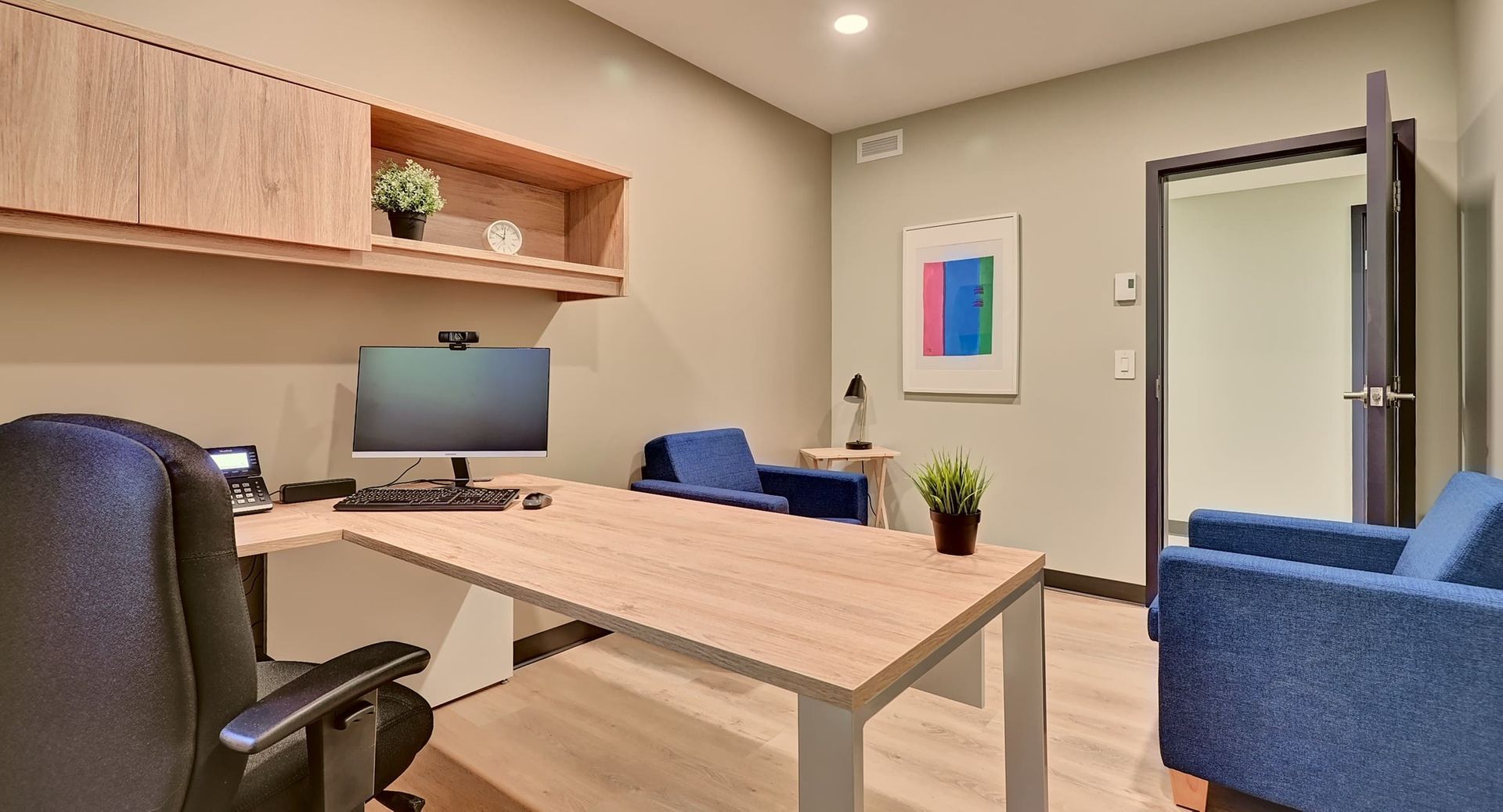 a small office with a desk and chair and a picture on the wall