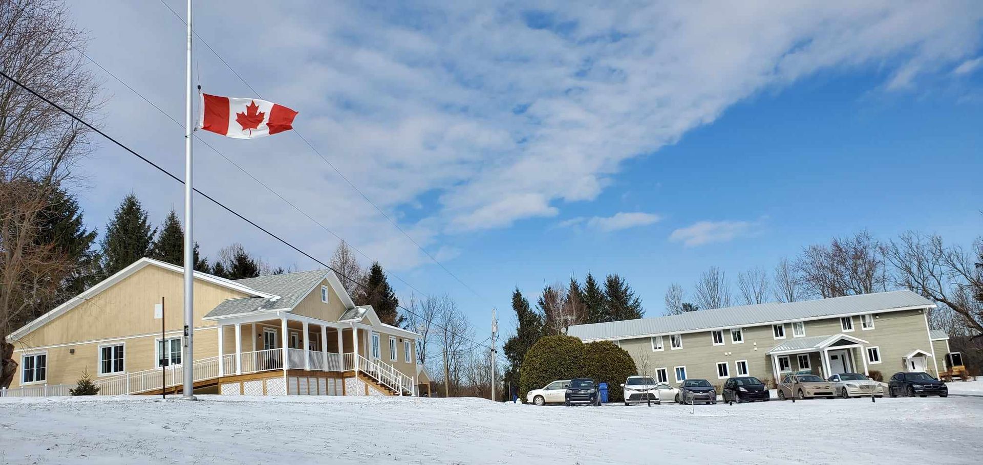 a canadian flag is flying in front of a house in the snow