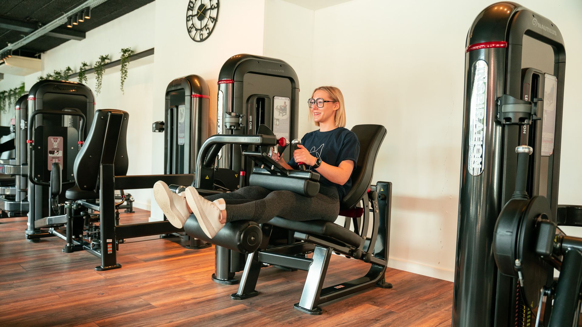 Een vrouw zit op een leg extension-apparaat in een sportschool.