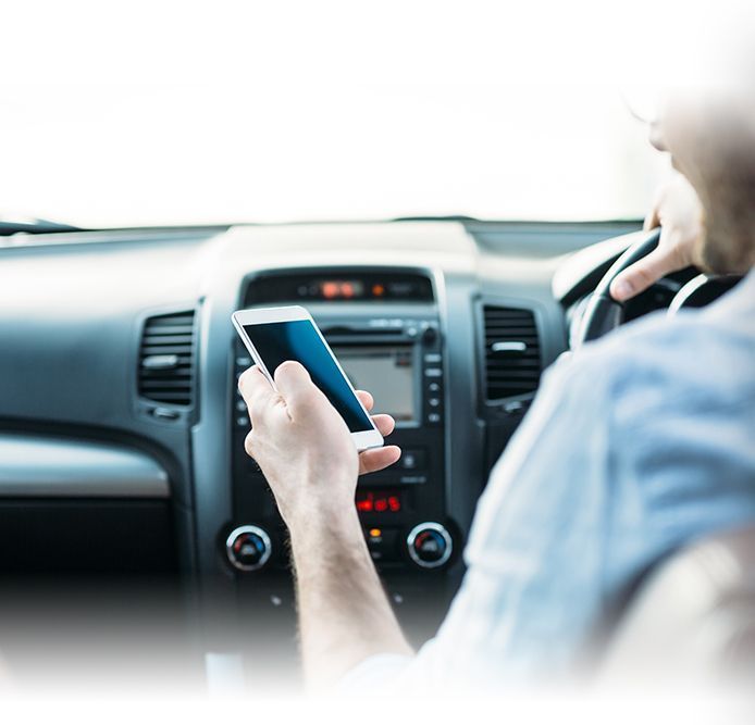 Person in car using a phone while driving. | Quality Car Truck Repair