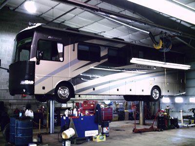 RV lifted on a hydraulic hoist inside a mechanic's shop for maintenance. | Quality Car & Truck Repair