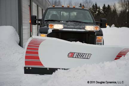 Black truck with snow plow pushing snow in front of a white building. | Quality Car & Truck Repair Inc