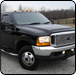 Black Ford F-350 truck with a chrome grill and dual rear wheels parked outdoors.  |  Quality Car & Truck Repair Inc
