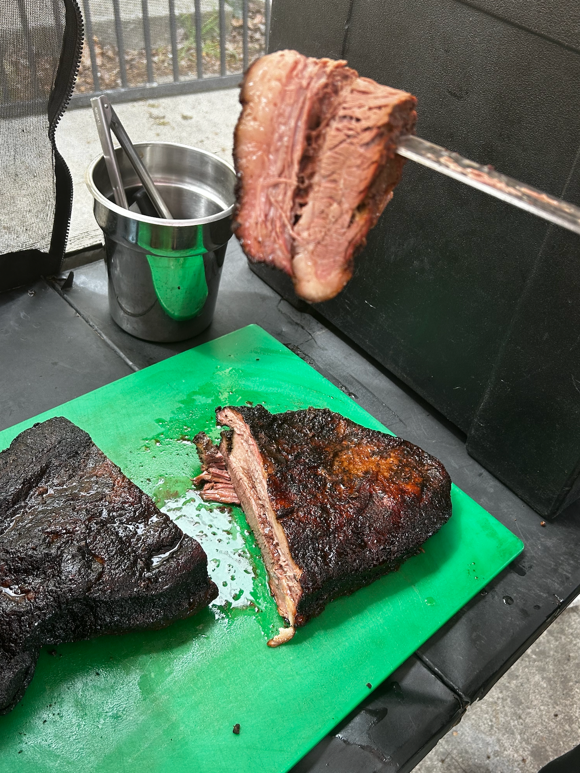 A piece of meat is hanging from a skewer on a cutting board.